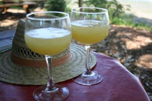 Two glasses of lemonade and a straw hat on a table