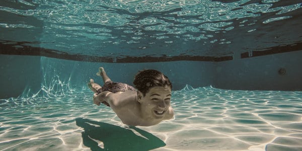 Call Me Edison Boy swimming under water in swimming pool.