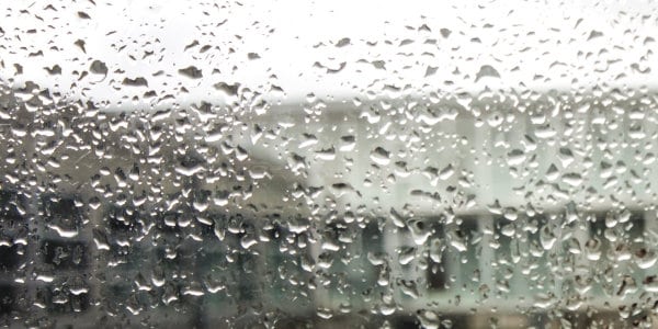 Raindrops on window with building in background.