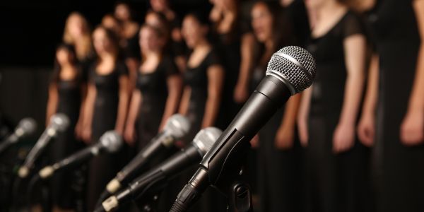 A choir standing behind a row of microphones