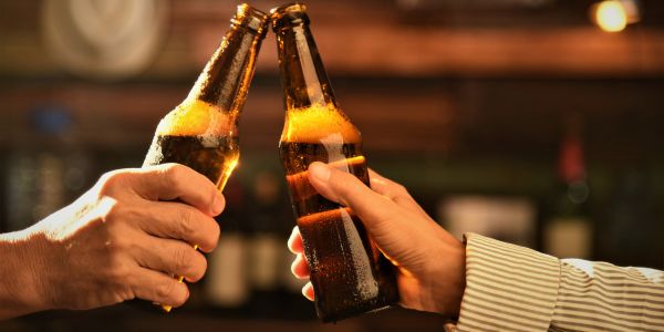 Two hands toasting, holding a beer bottle