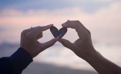 Male and female hand making a “love” sign out of mussel shells Male and female hand making a “love” sign out of mussel shells