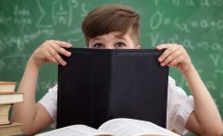 Schoolboy hiding behind a book, embarrased Schoolboy hiding behind a book, embarrased
